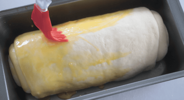 unbaked loaf being brushed with an egg wash
