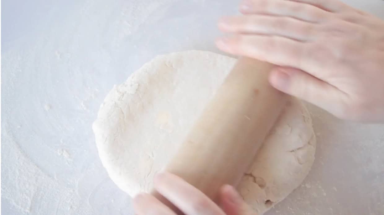 Rolling pin rolling out biscuit dough.