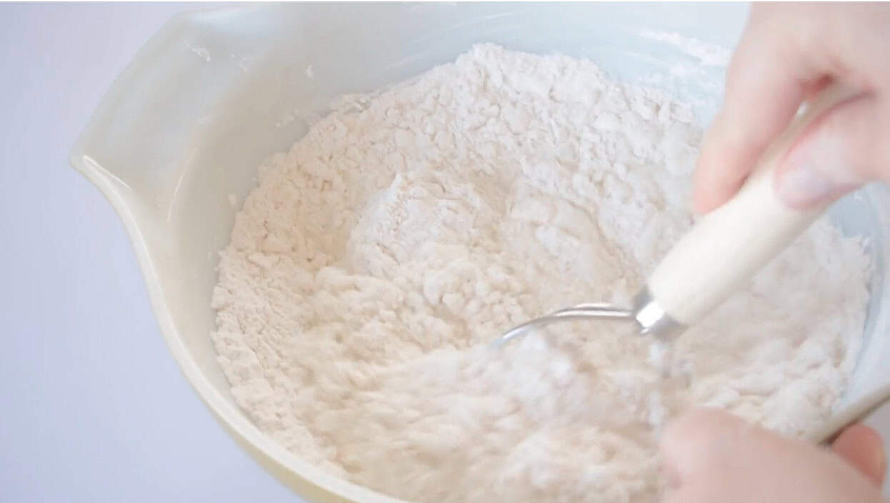 Mixing bowl with biscuit dough and Danish dough whisk.