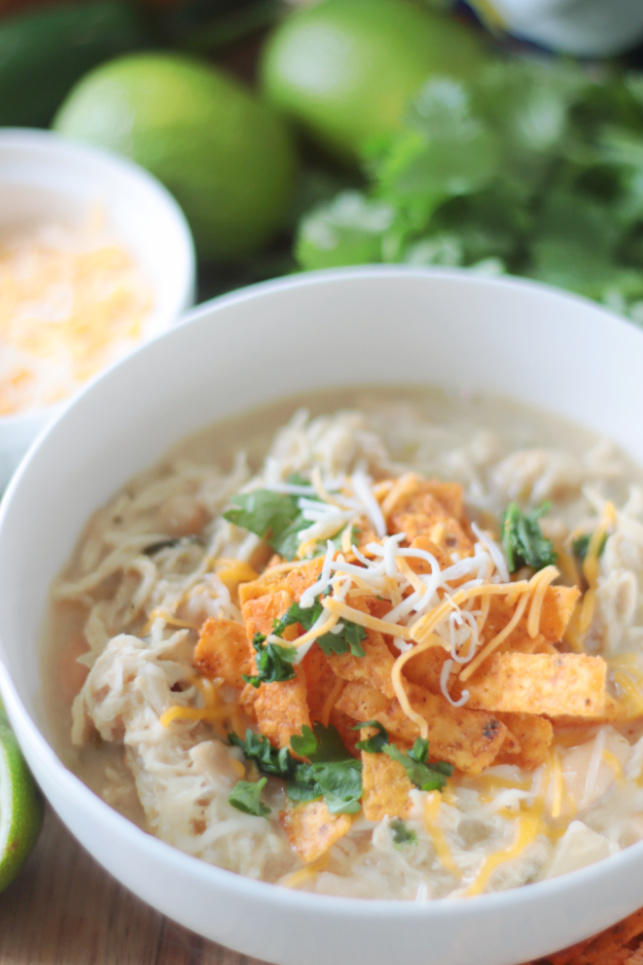 bowl of chicken chili with shredded cheese and tortilla strips