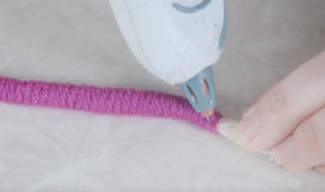 dot of hot glue at the end of a yarn wrapped rope