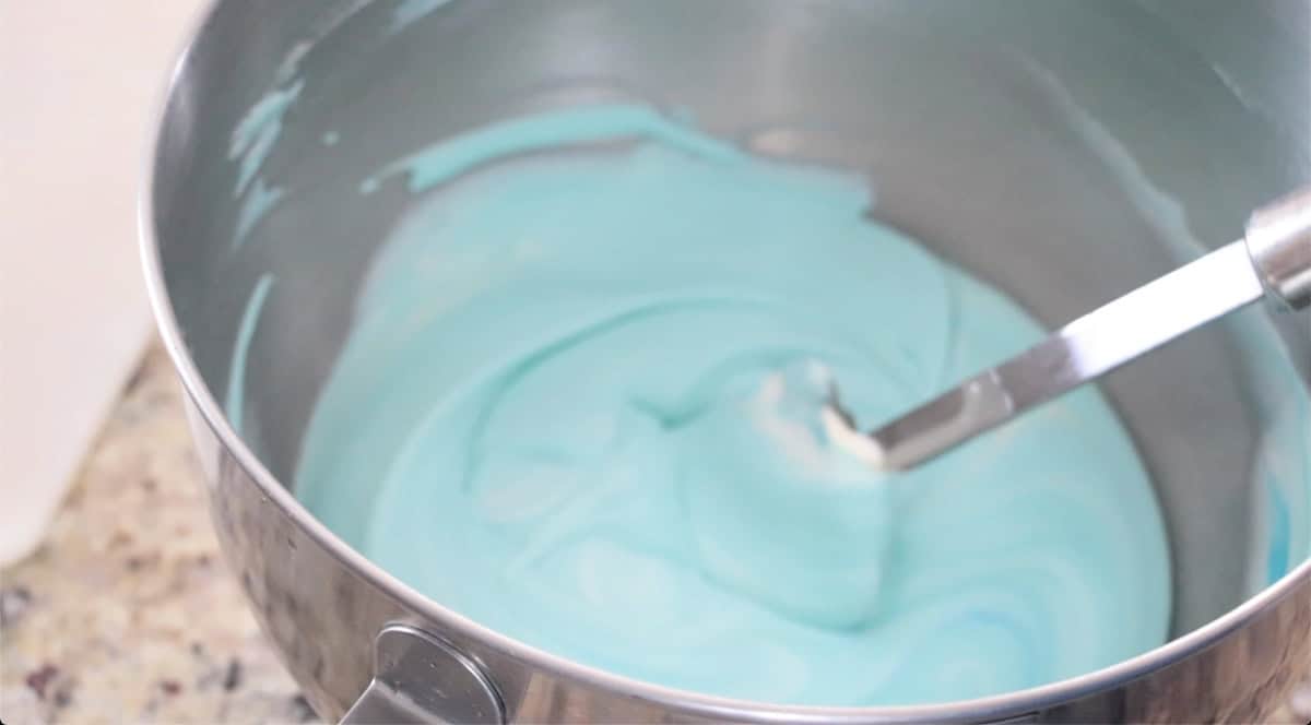Metal mixing bowl with blue ice cream mixture.