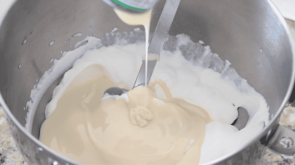 Sweetened condensed milk and whipping cream in large metal mixing bowl.