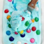 Loaf pan of blue bubble gum ice cream and ice cream scoop.