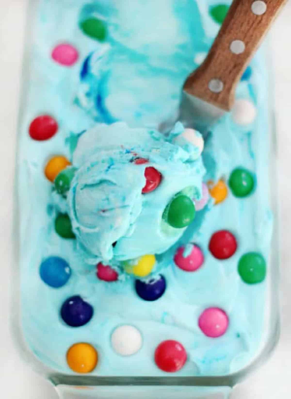 Loaf pan of blue bubble gum ice cream and ice cream scoop.