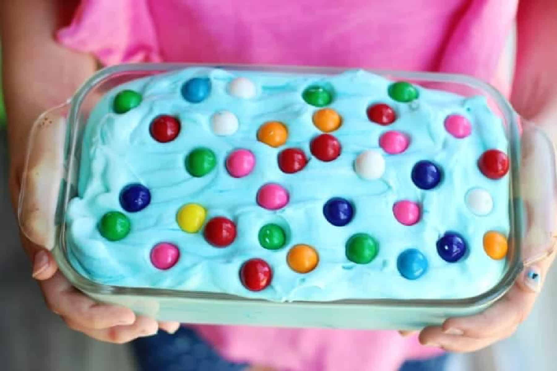 Hands holding pan of bubble gum ice cream with gum balls.