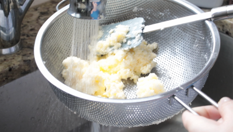 butter in a strainer being rinsed in sink