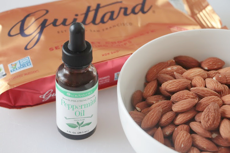 bag of chocolate chips, bottle of peppermint oil and a bowl of raw almonds