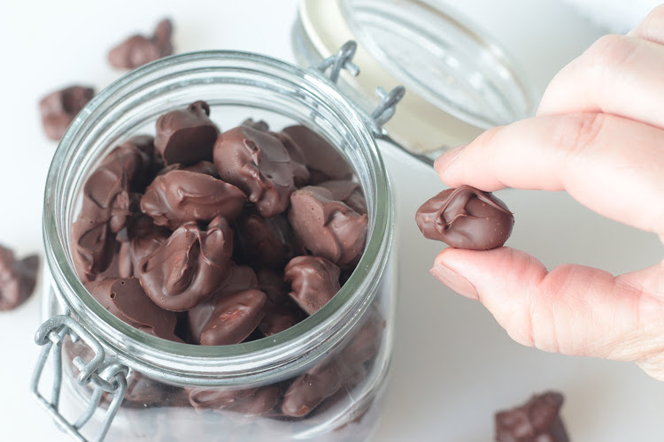 hand holding thin mint almond next to glass jar