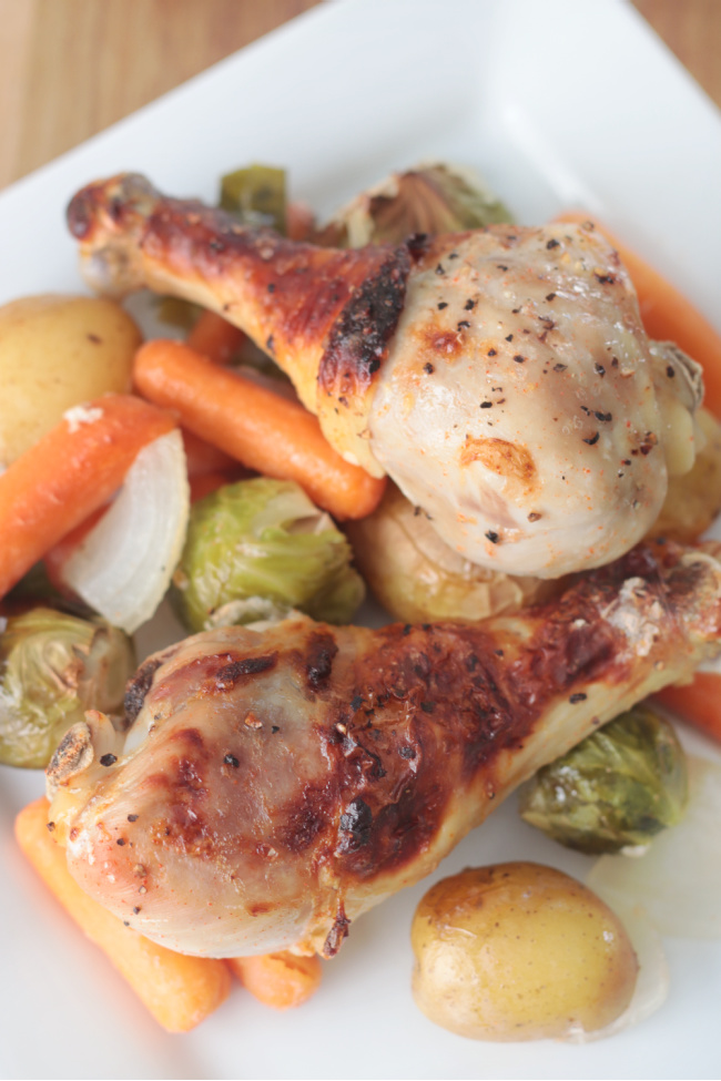 two roasted chicken legs on plate with vegetables