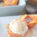 white plate with baked peach halves and vanilla ice cream