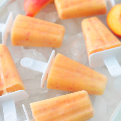 fresh peach popsicles on a tray of ice
