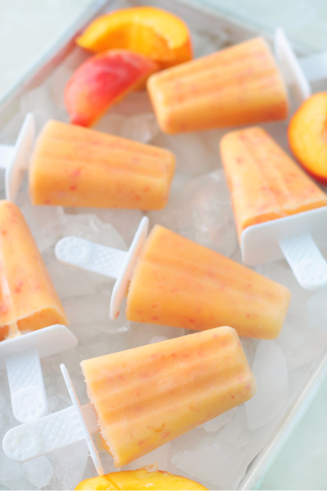 fresh peach popsicles on a tray of ice