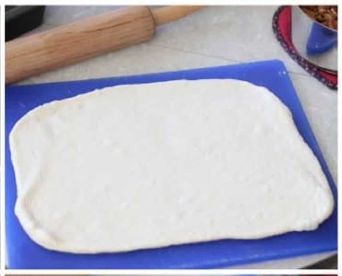 Blue cutting board with dough rolled out into a rectangle.