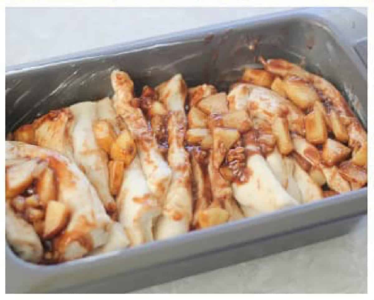 Loaf pan of bread slices with apple filling.