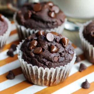 Double chocolate pumpkin muffins on orange striped napkin.
