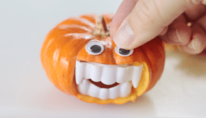 hand adding eye to mini pumpkin