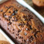 White loaf pan of pumpkin bread next to 3 muffins.