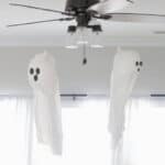 Two garbage bag ghosts hanging from the ceiling fan.