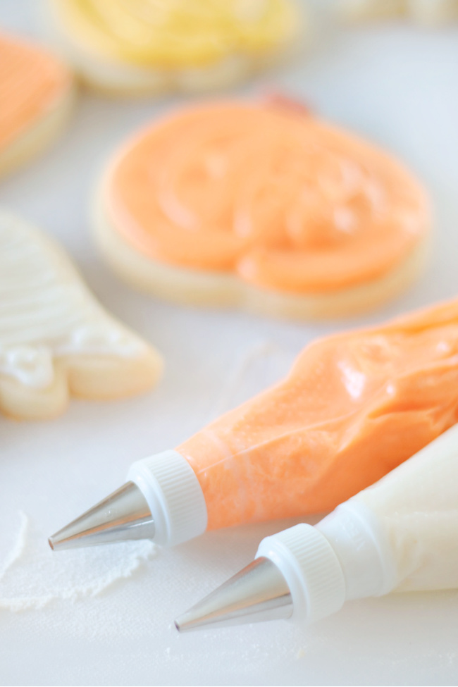 piping bags filled with white and orange buttercream frosting