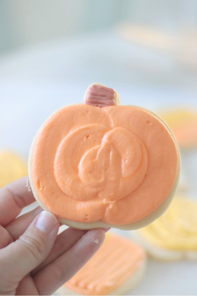 hand holding pumpkin sugar cookie