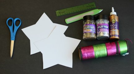 white paper stars, curling ribbon and bottles of glitter