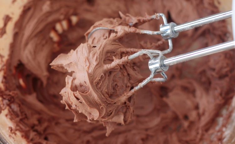 electric mixer beaters covered in chocolate frosting