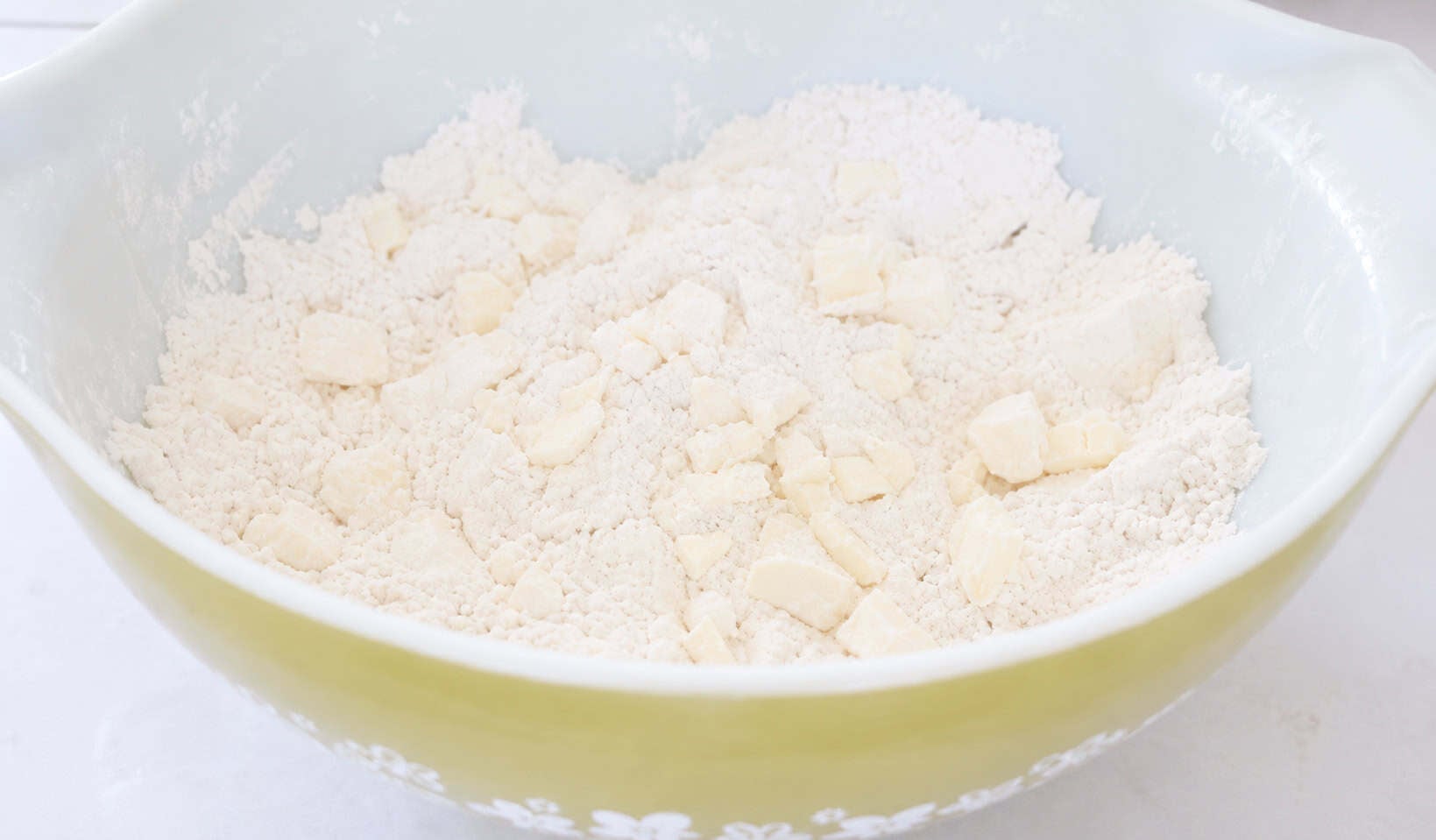Bowl of butter and flour cut into crumbs.