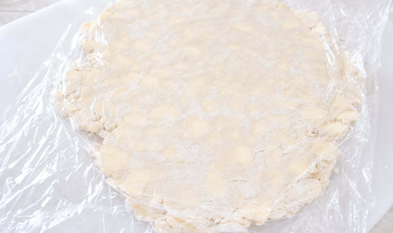 Turnover dough rolled out with plastic wrap over it.