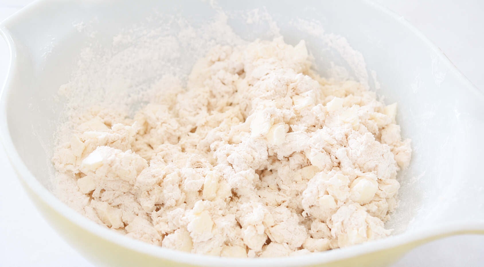 Bowl of butter and flour cut into crumbs.