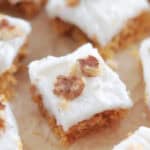 Frosted carrot cake bars on parchment paper.