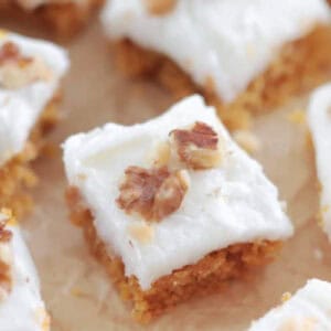Frosted carrot cake bars on parchment paper.