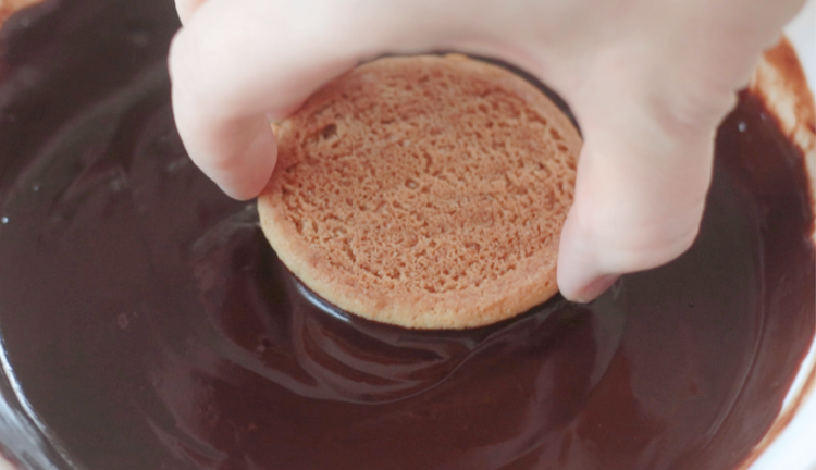 hand dipping cookie into chocolate glaze