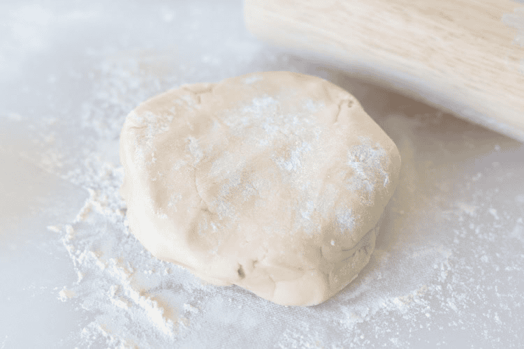 Ball of sugar cookie dough on floured surface.