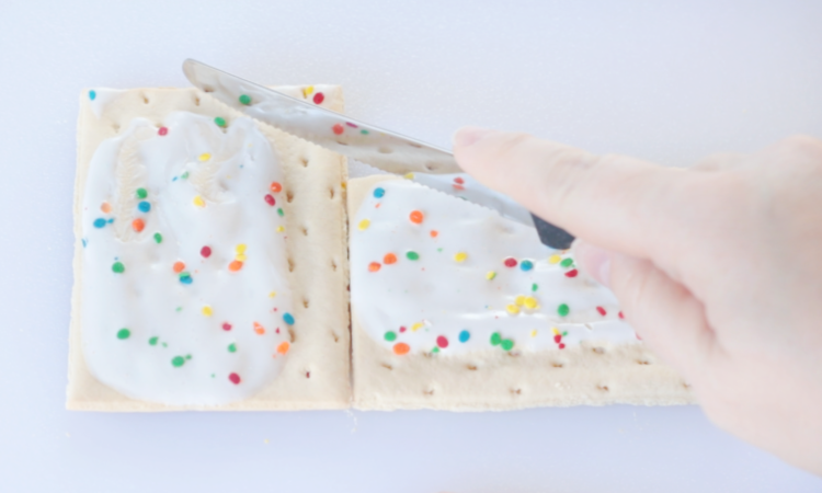 hand with knife cutting pop tart on an angle for a roof