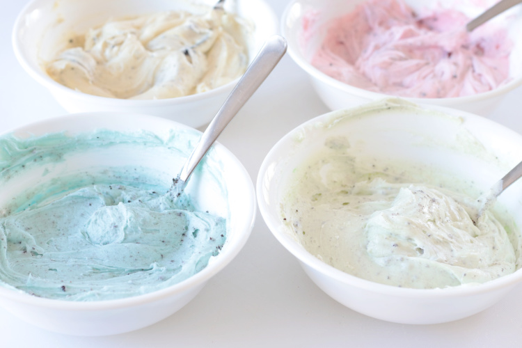 four bowls of pastel buttercream frosting