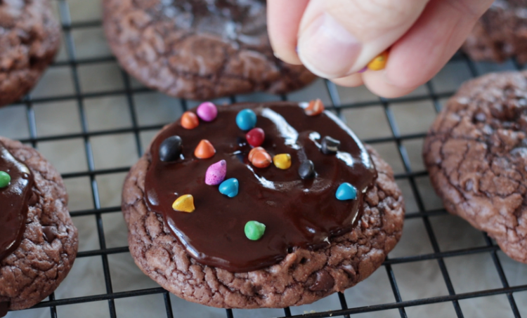 hand sprinkling cosmic rainbow chips over chocolate cookies