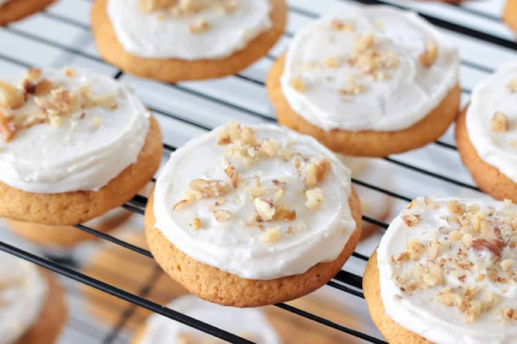Frosted carrot cake cookies on cooling rack.