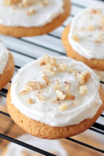 Frosted carrot cake cookies topped with chopped nuts.