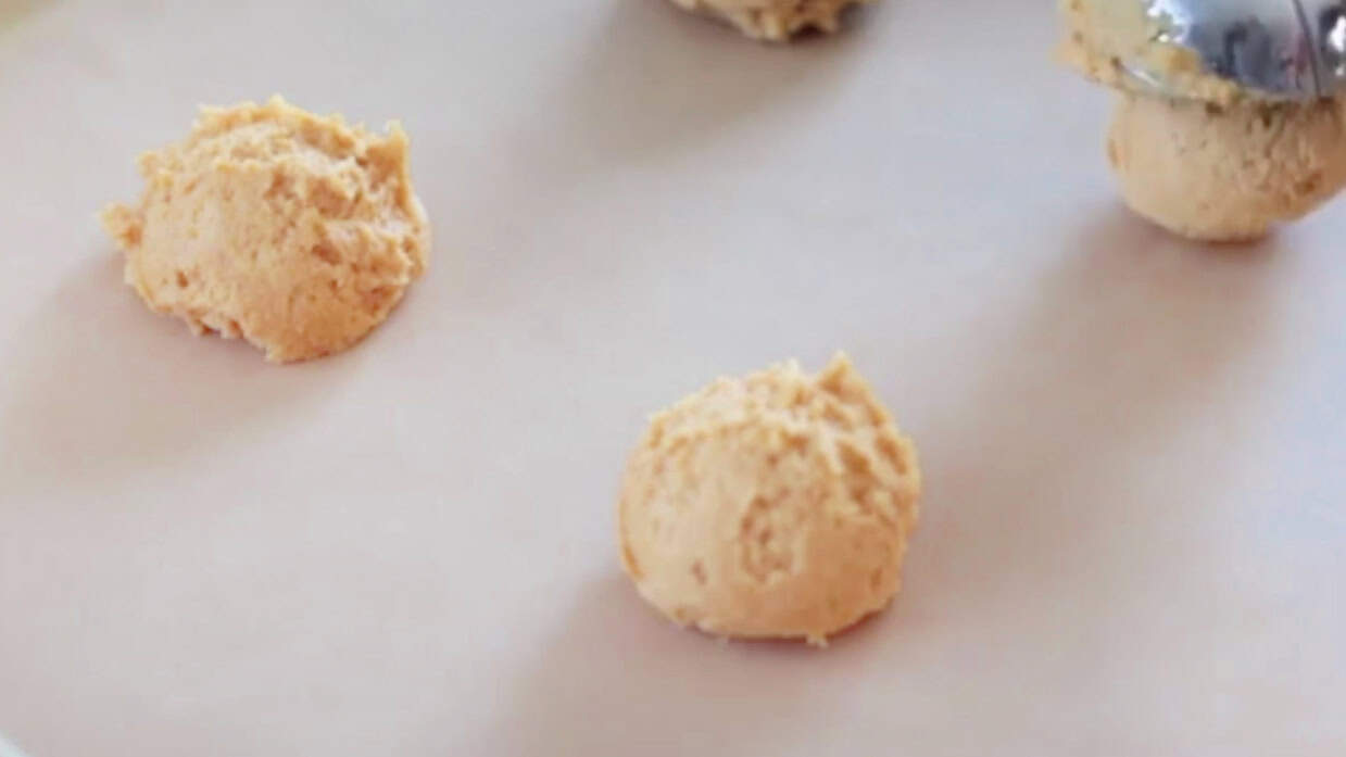 Scoops of carrot cake cookie dough on baking sheet lined with parchment paper.
