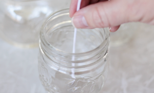 jar with hand adding a wick inside