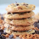Stack of freshly baked chocolate chip cookies with chocolate chips and pretzels.