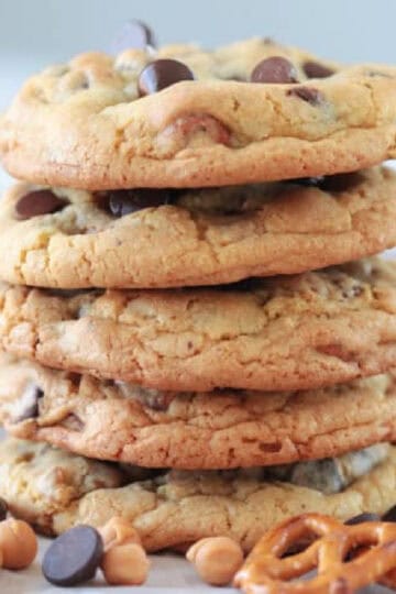 Stack of freshly baked chocolate chip cookies with chocolate chips and pretzels.