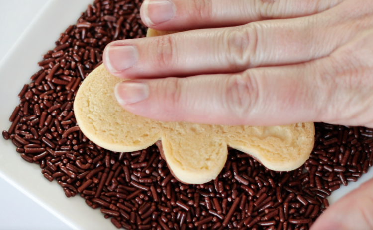 cookie being pressed into chocolate sprinkles