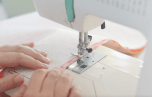 sewing machine and hands pushing fabric through machine