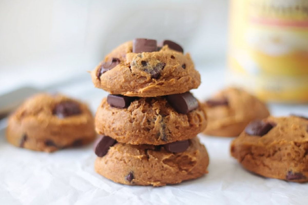 3 pumpkin cookies stacked on parchment paper.