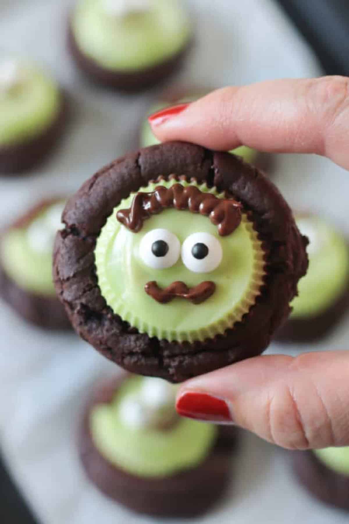 Hand holding chocolate Frankenstein cookie.