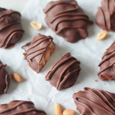 peanut cluster cut in half and clusters on parchment paper
