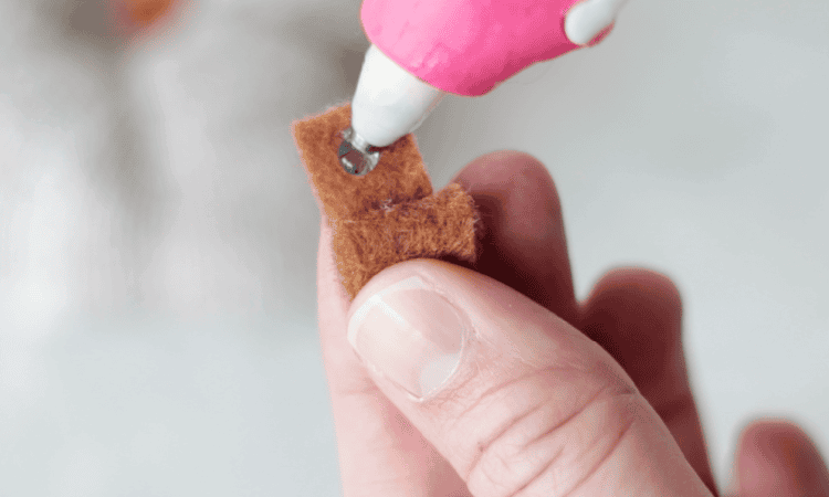 hot glue gun adding dot of glue to felt