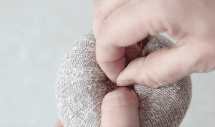 hand poking needle and thread into filled sock
